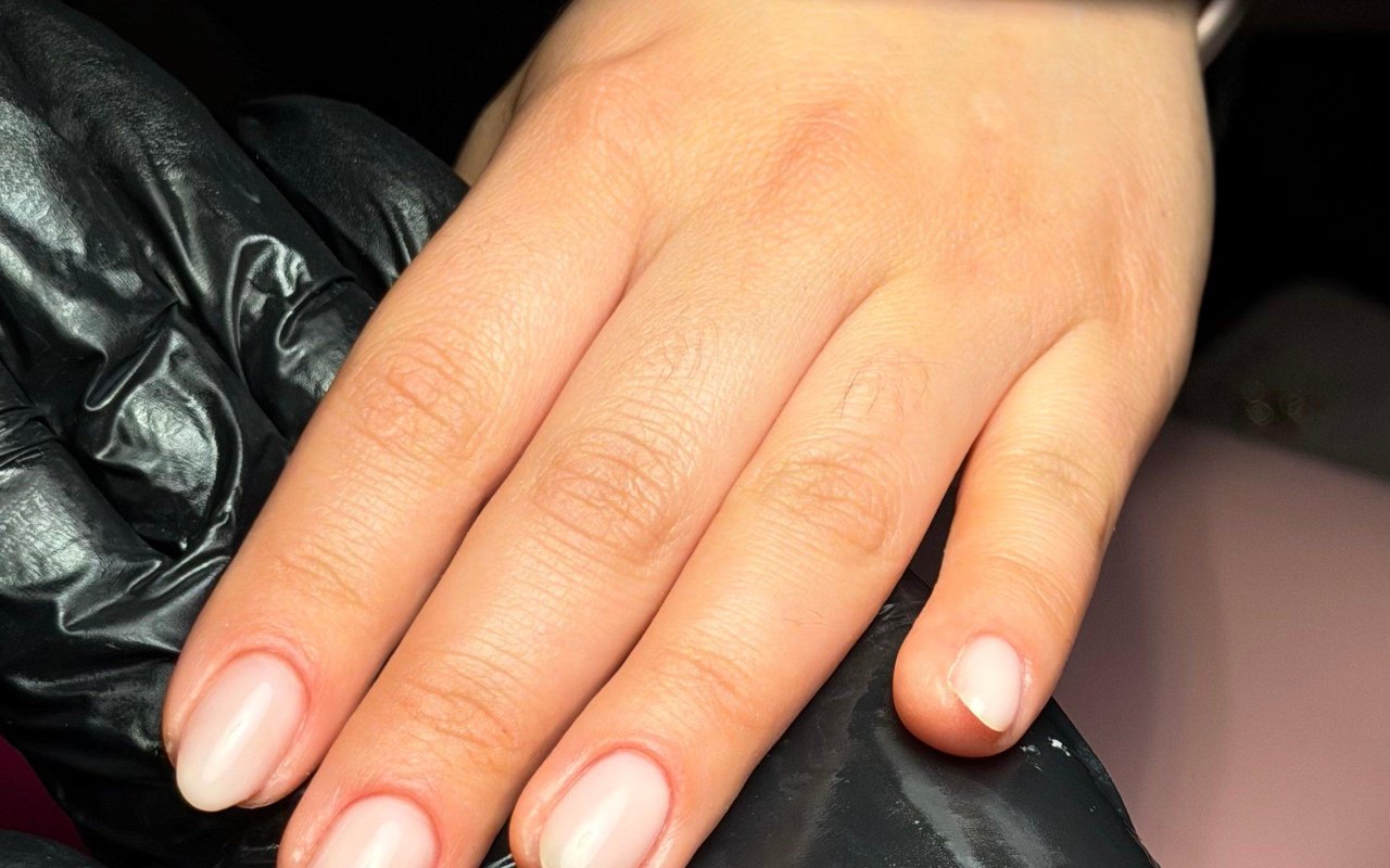 Nude natuurlijke nagels op een zwarte handschoen