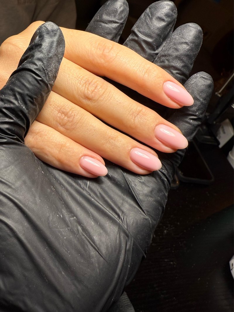 Nude nagels op een zwarte handschoen