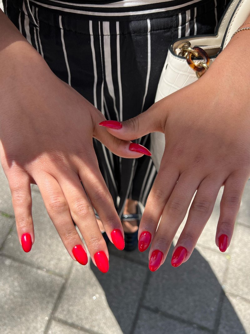 Rode nagels, handen op een gestreepte broek