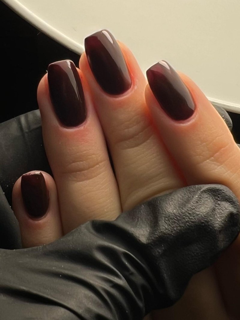Chocoladebruine nagels op een zwarte handschoen